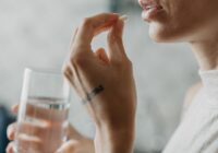 Woman about to take a pill holding a glass of water in her other hand
