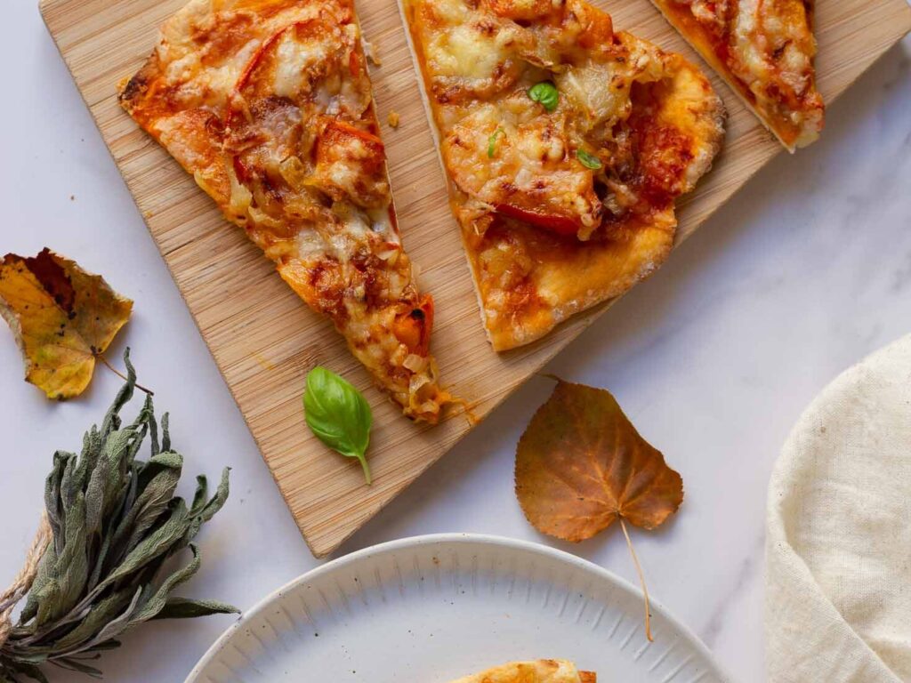 sliced of pizza laid out on wooden cutting board