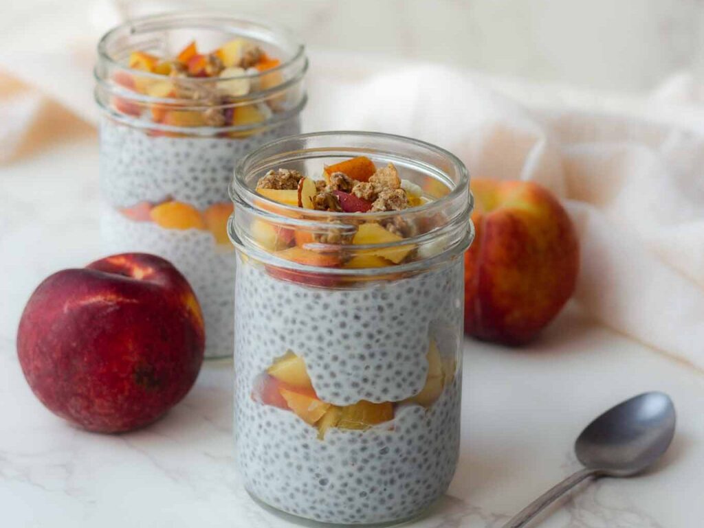 chia seed pudding layered with peaches and granola in mason jar