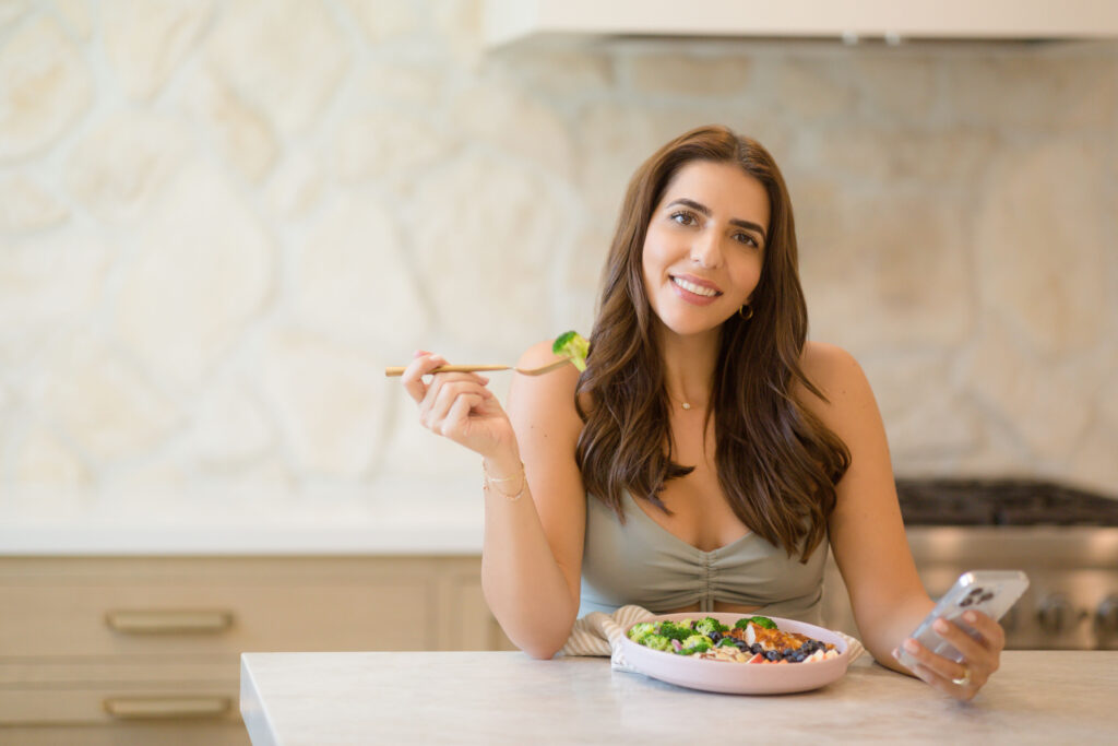 woman sitting at counter with plate of food holding fork in hand