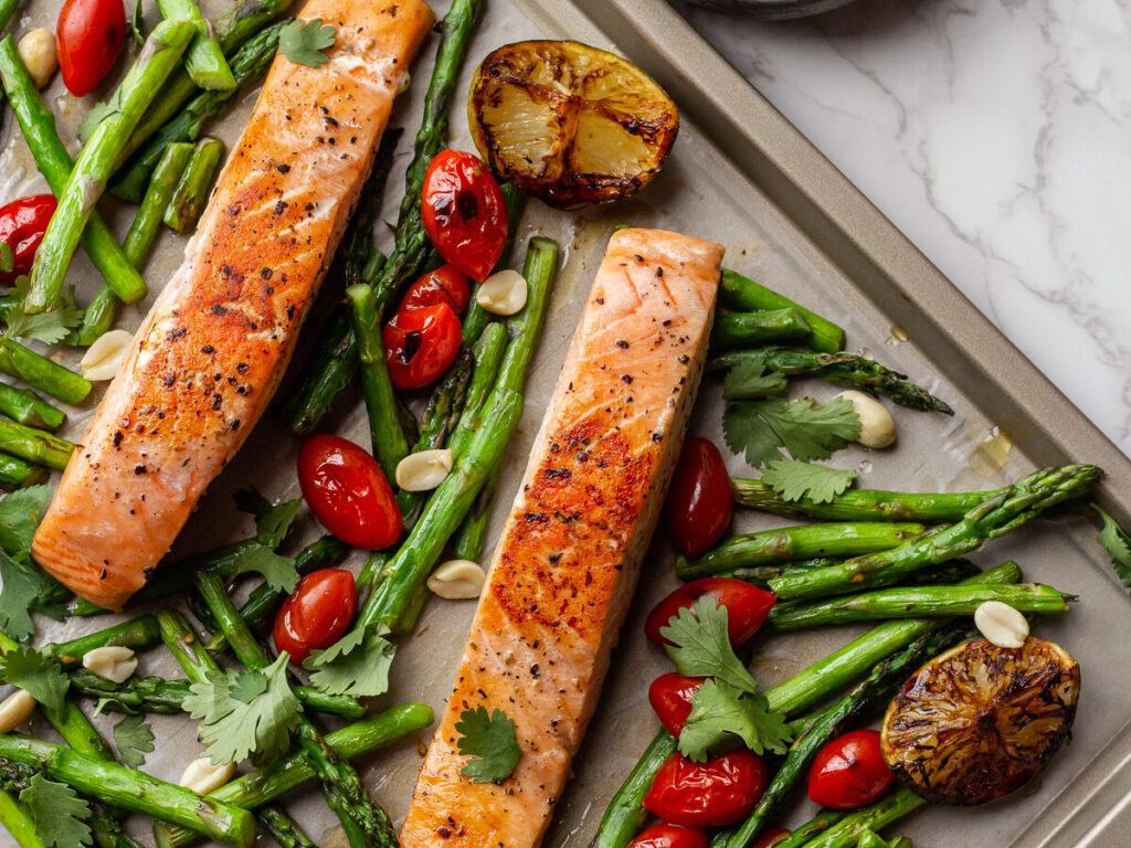 sheet pan with slices of salmon and roasted asparagus and cherry tomatoes