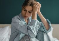 Woman sitting on a bed looking sick