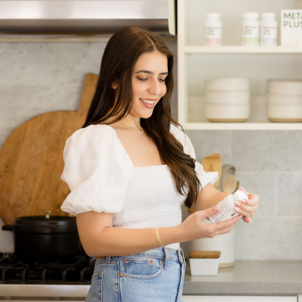 woman smiling looking at metabolism plus bottle in her hand