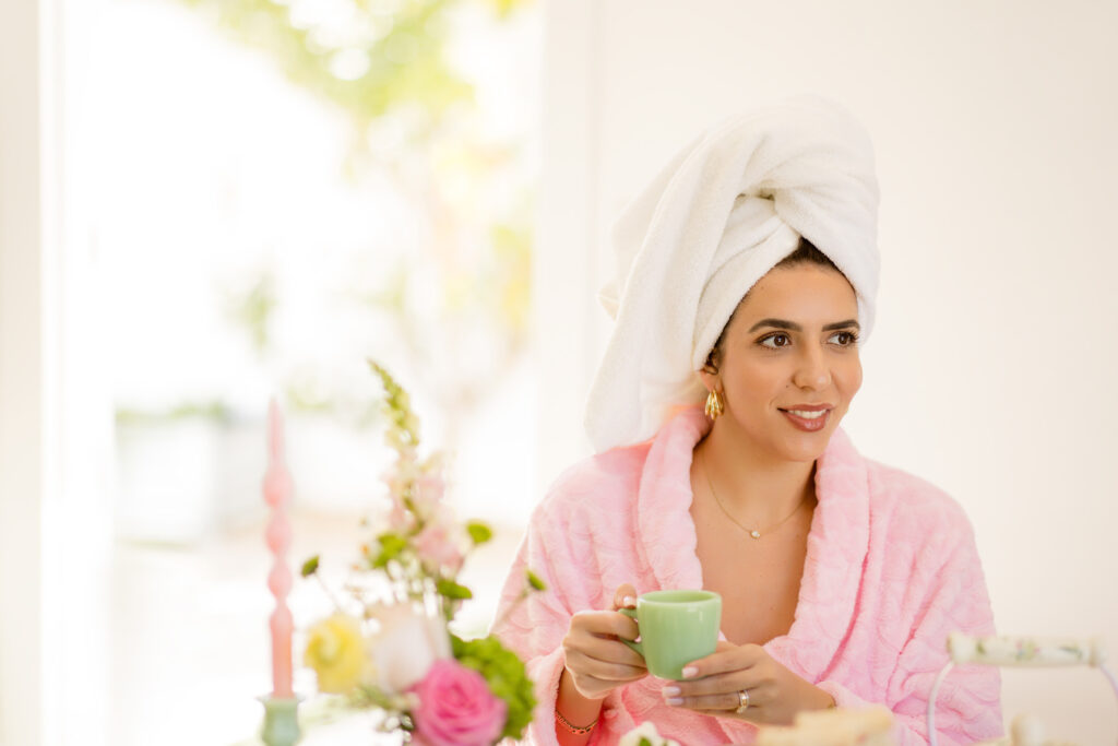 tallene in head wrap and bathrobe holding a tea cup