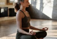 woman sitting upright in a meditation pose on a yoga mat