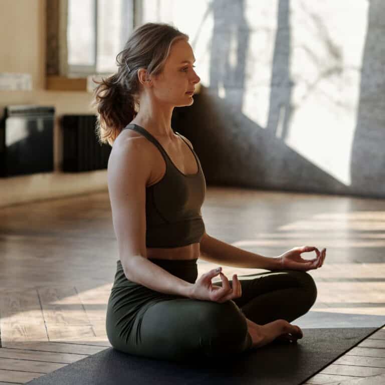woman sitting upright in a meditation pose on a yoga mat