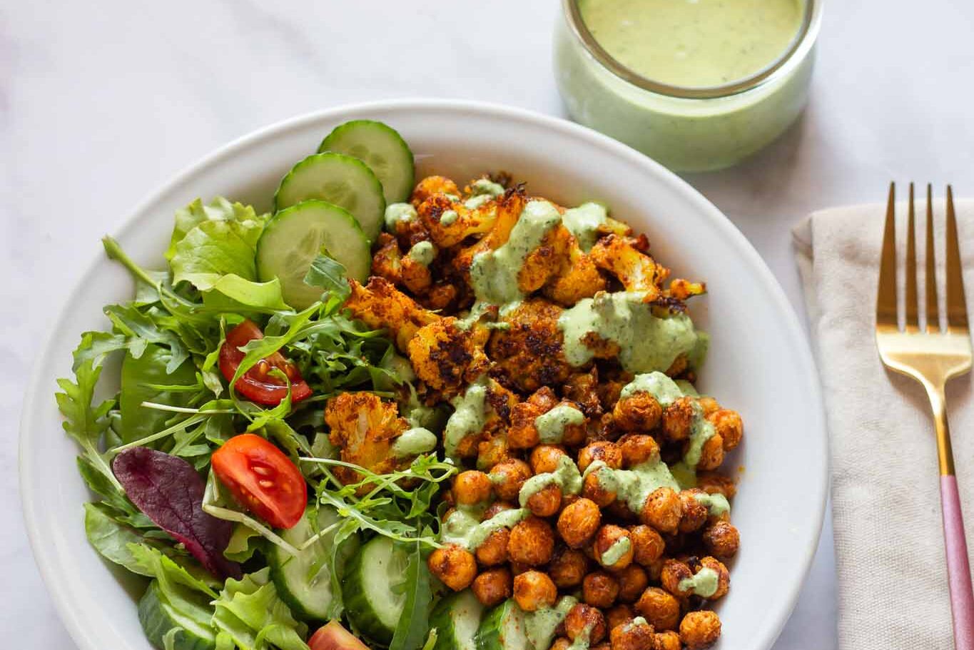 bowl full of roasted chickpeas, salad mix, cucumbers, and chicken