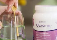 ovasitol canister sitting next to a glass of water with gold spoon