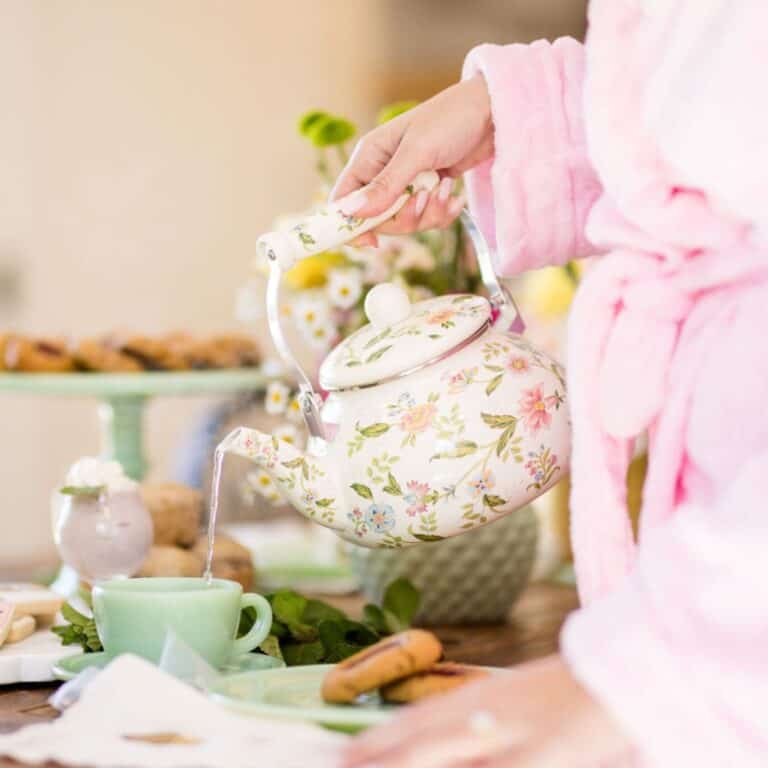 hand holding a teapot being poured into a teacup