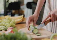 zoomed in view of someone's hands holding and cutting a cucumber