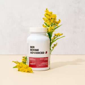 Berberine supplement bottle in with two golden flowers next to it