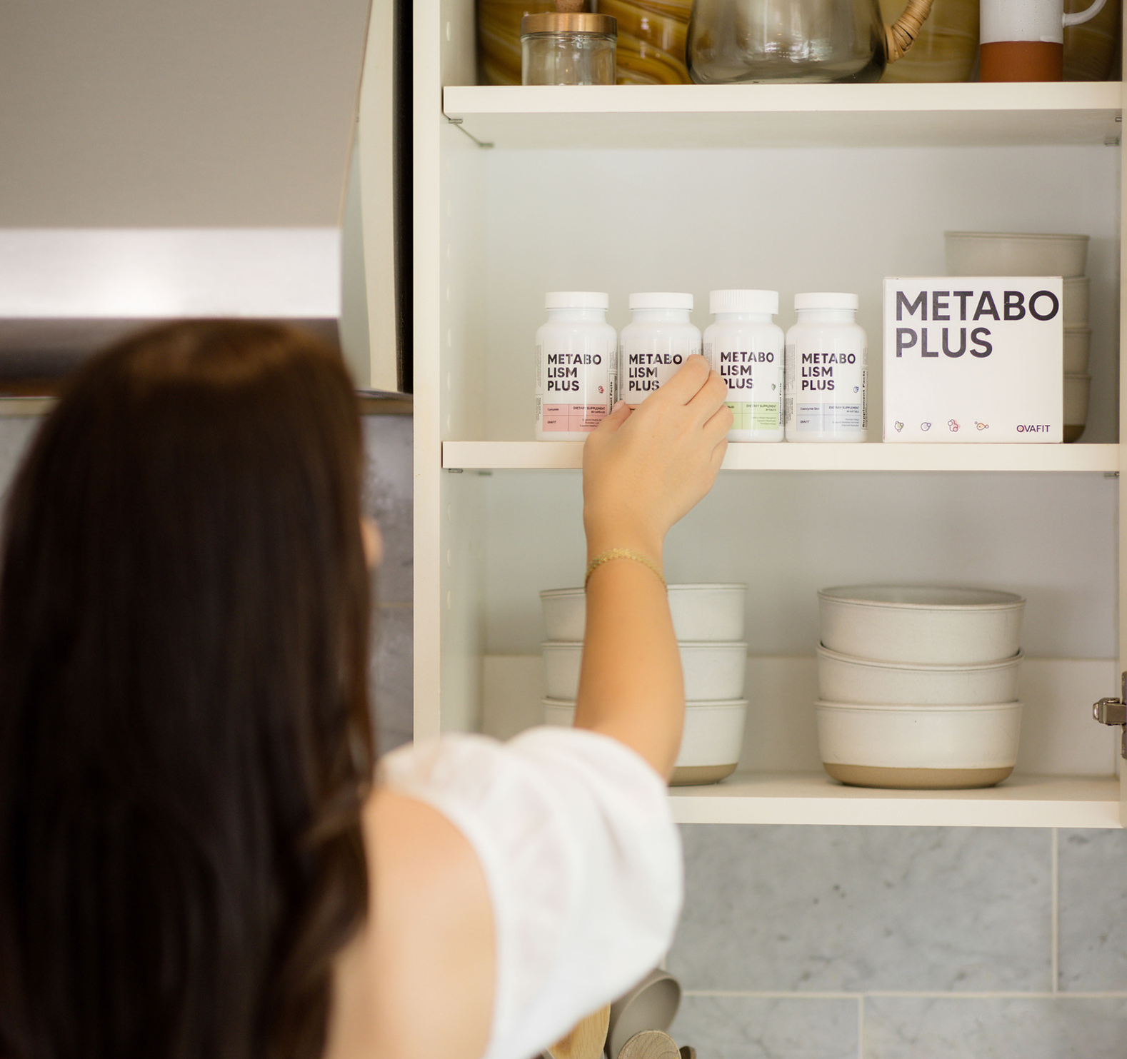 woman reaching into cabinet and grabbing metabolism plus supplements