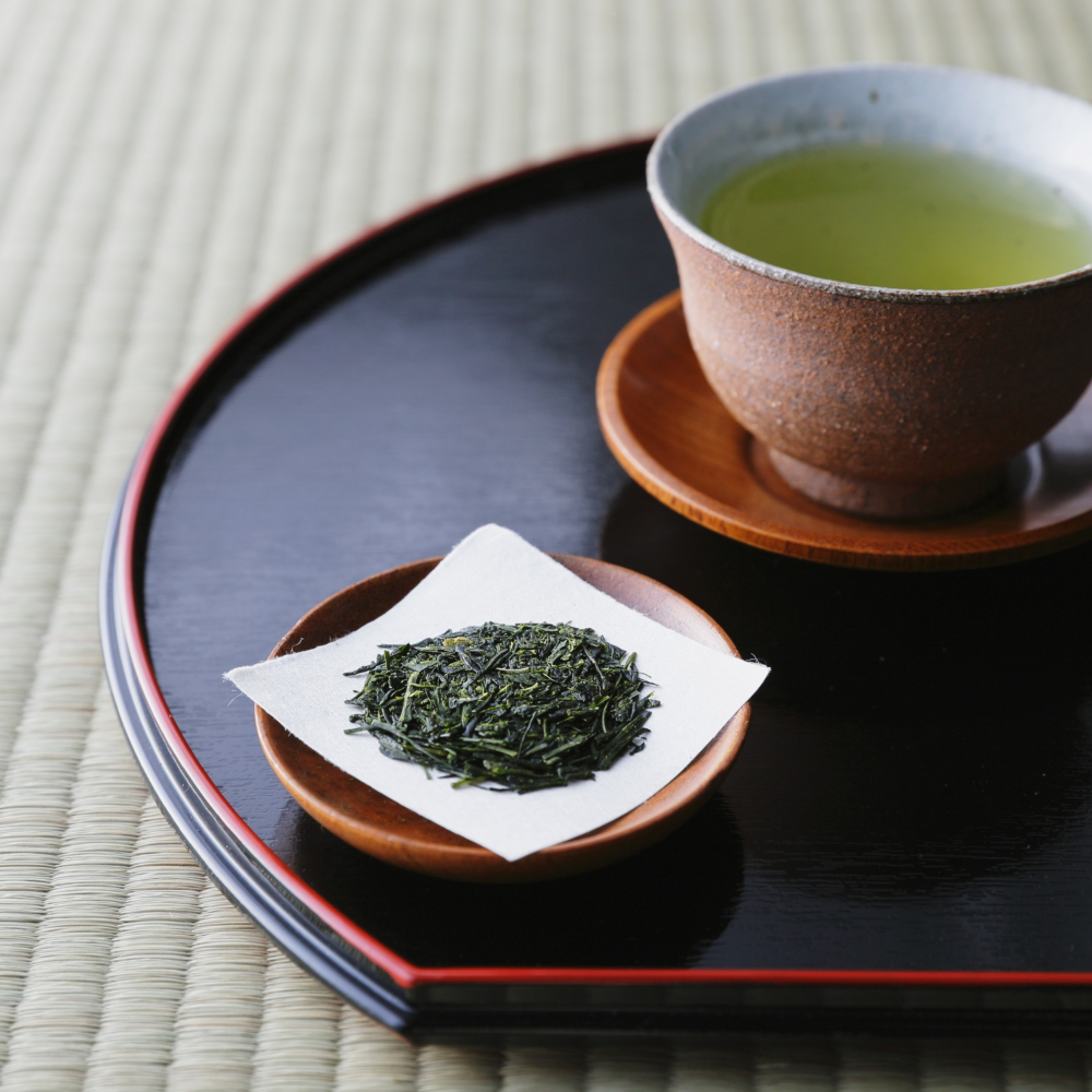 mug of green tea next to dry green tea leaves